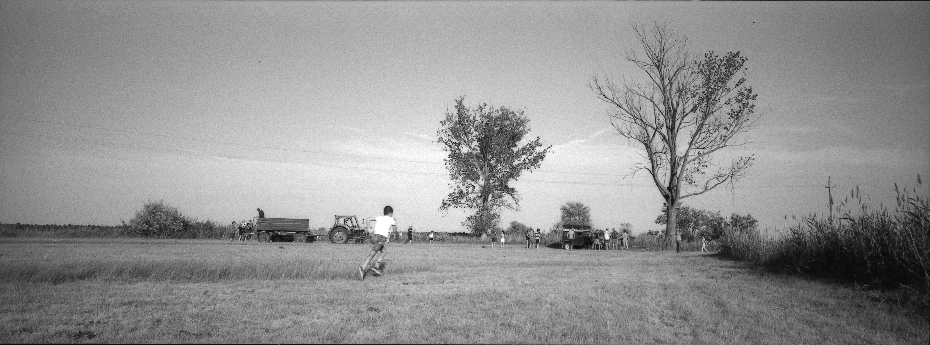A child running across the field while the TÖK Camp team gathers near the trees